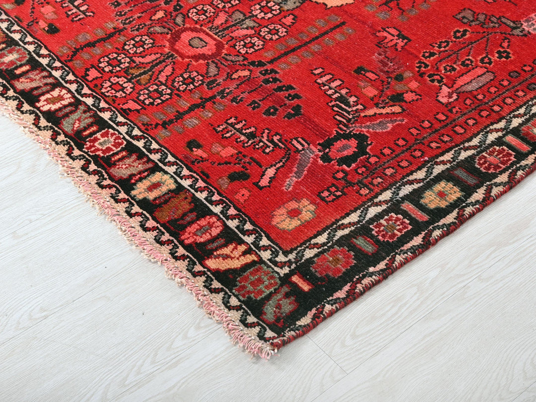 a red oriental rug on a white wooden floor