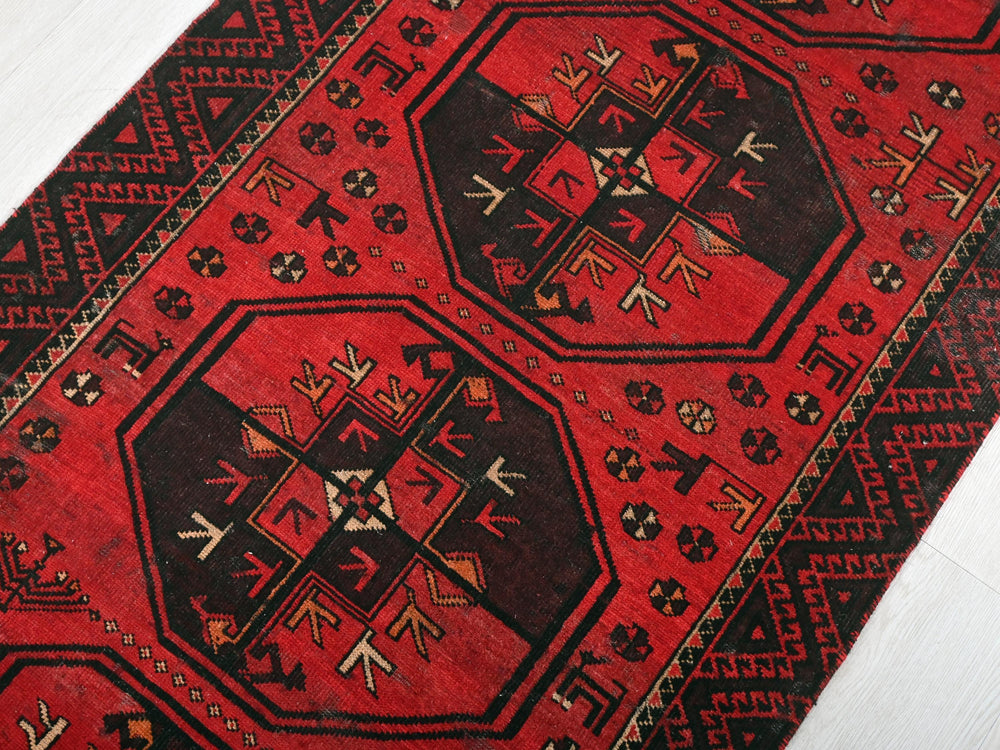 a red and black oriental rug on a white floor