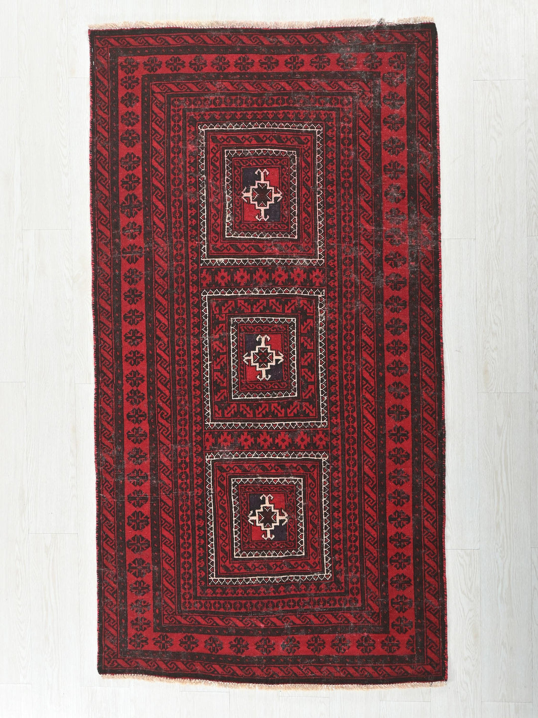 a red and black rug on a white floor