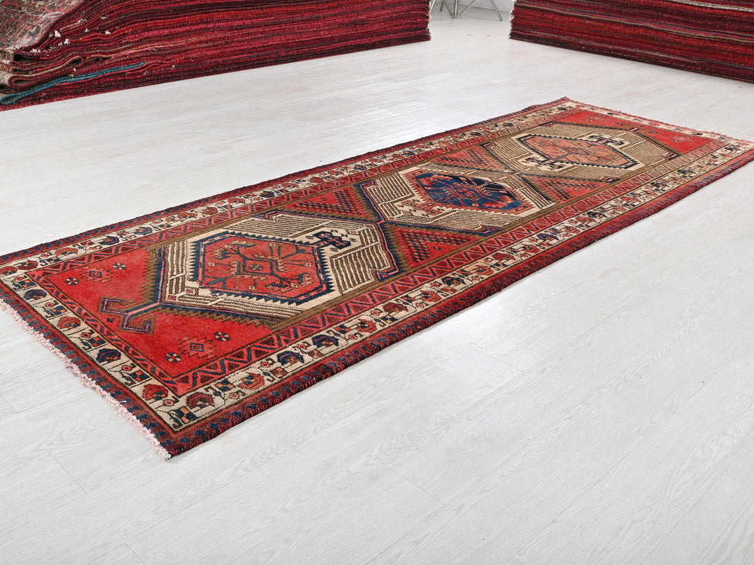 a red rug on a white floor next to a pile of red rugs