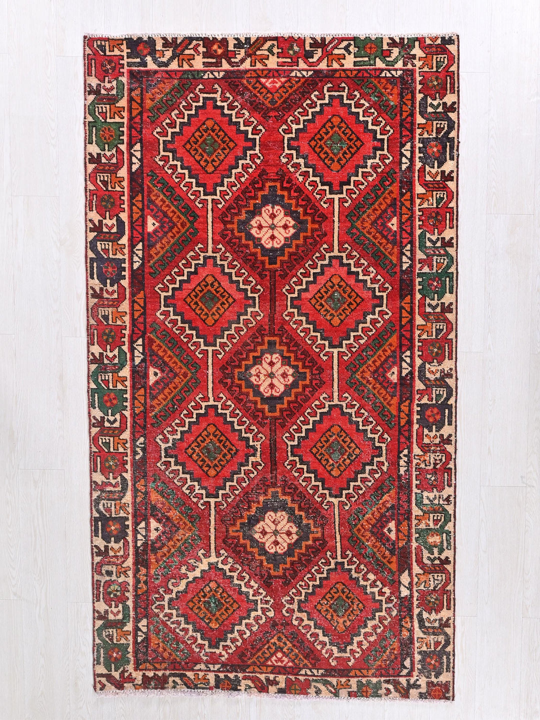 a red rug hanging on a white wall