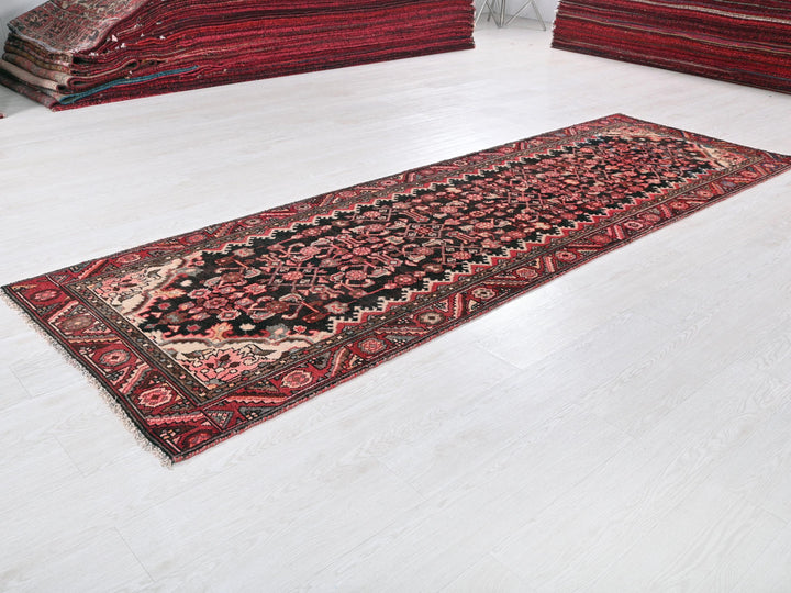 a red rug on a white floor next to a pile of rugs