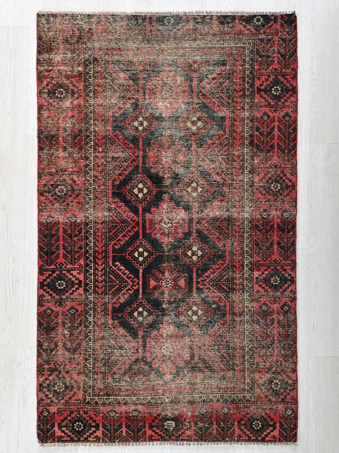 a red and black rug on a white floor