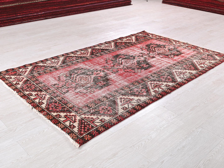 a red and black rug on a white floor