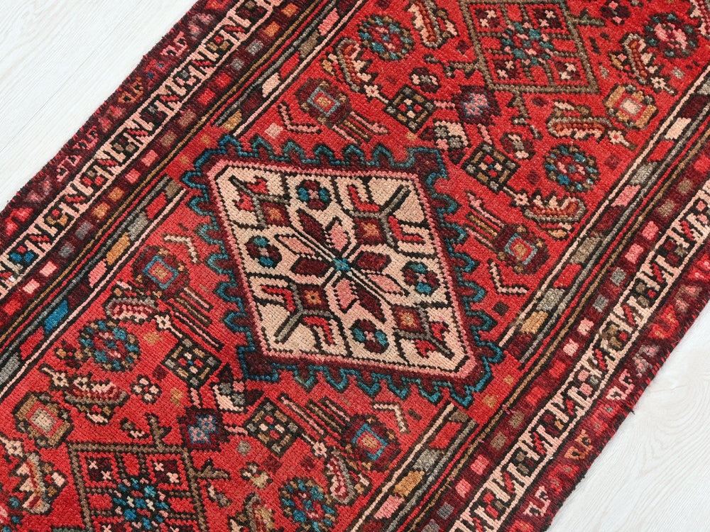 a red oriental rug on a white wooden floor