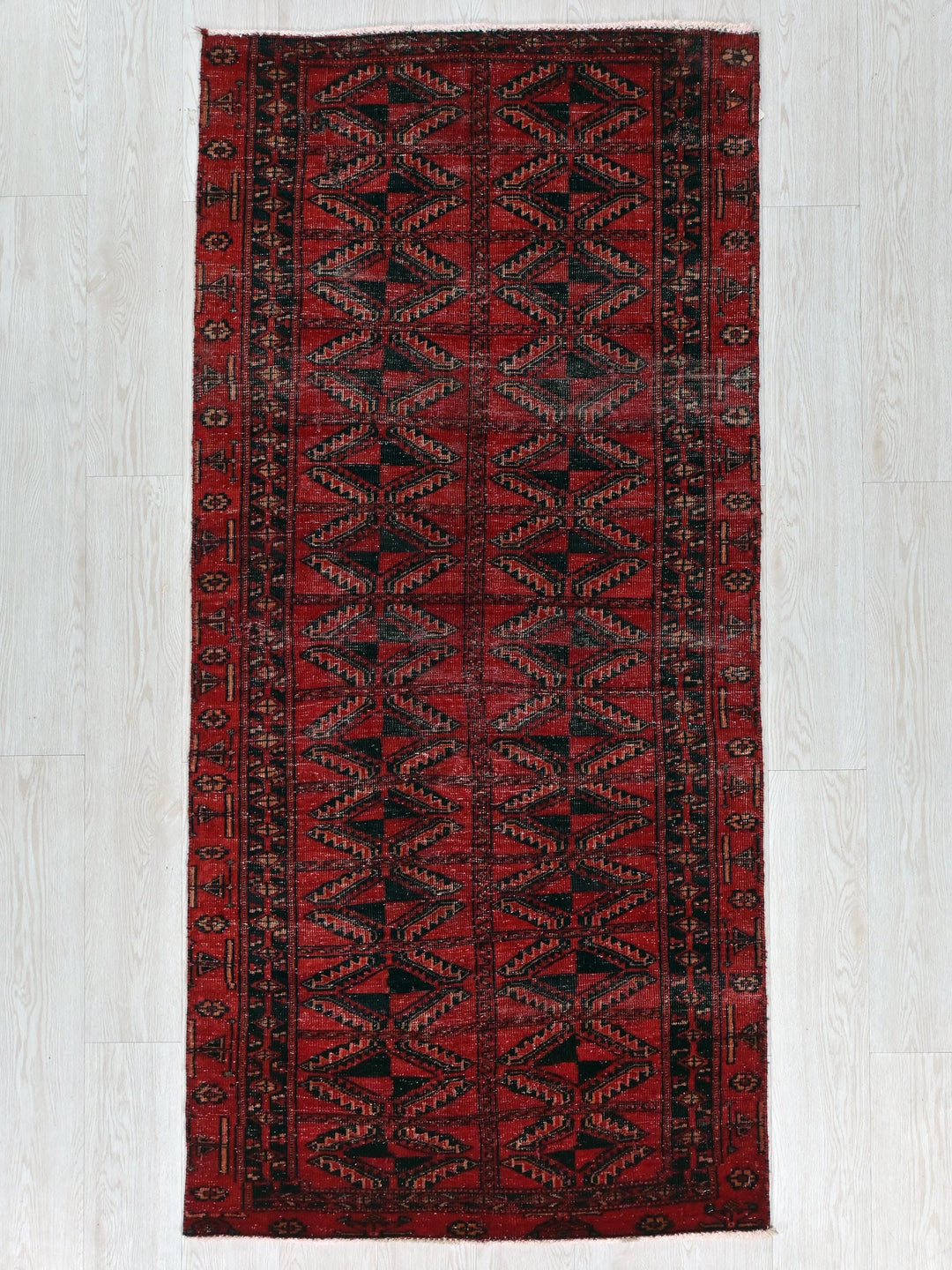 a red and black rug on a white floor