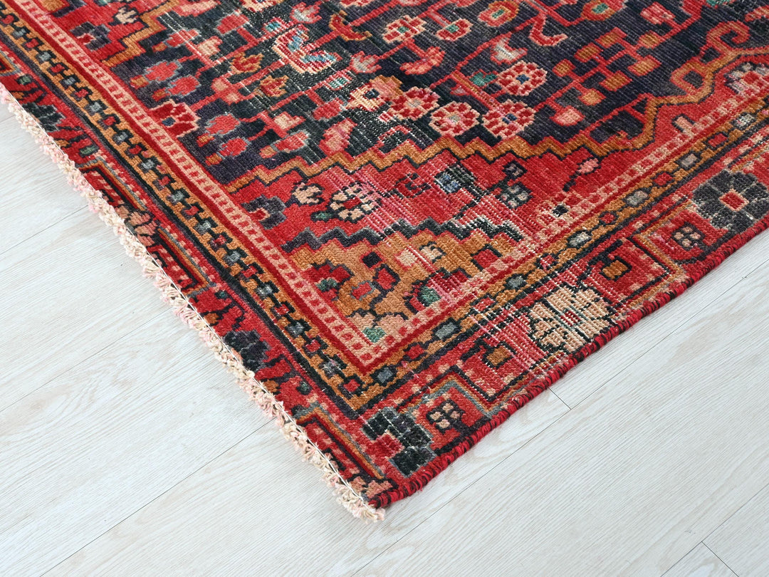 a red and black oriental rug on a white floor