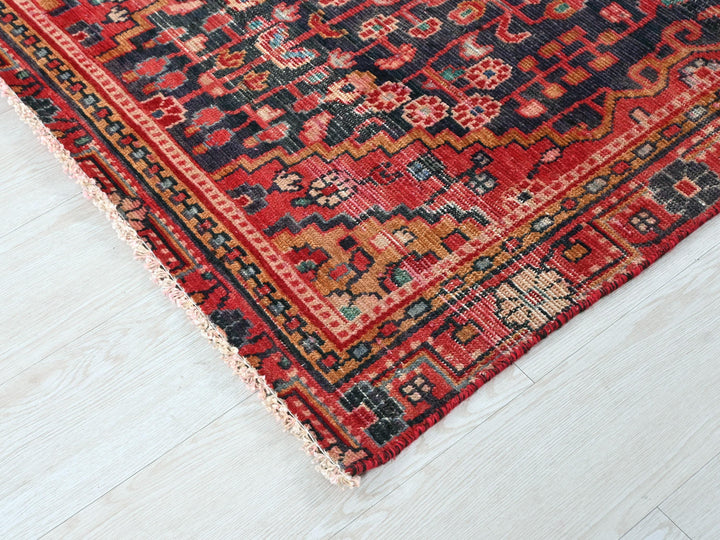 a red and black oriental rug on a white floor