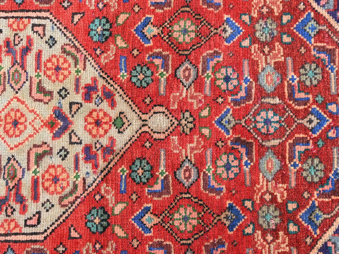 a red rug with a diamond shaped design on it
