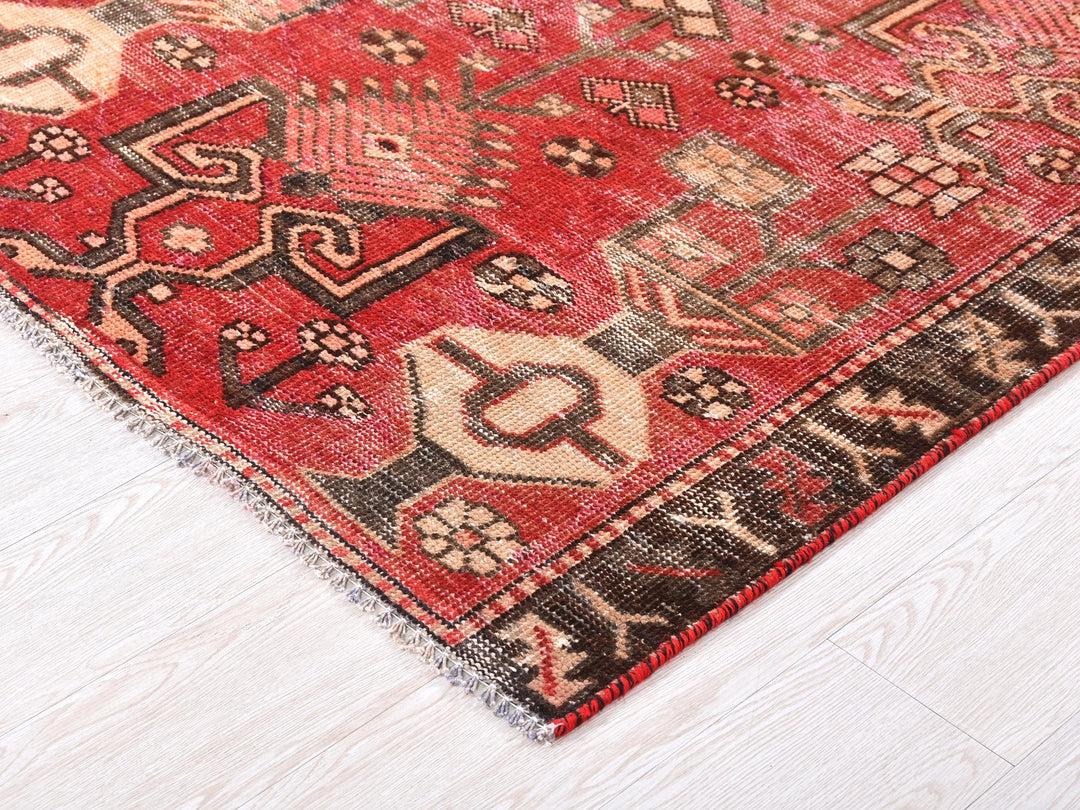 a red oriental rug on a white wooden floor
