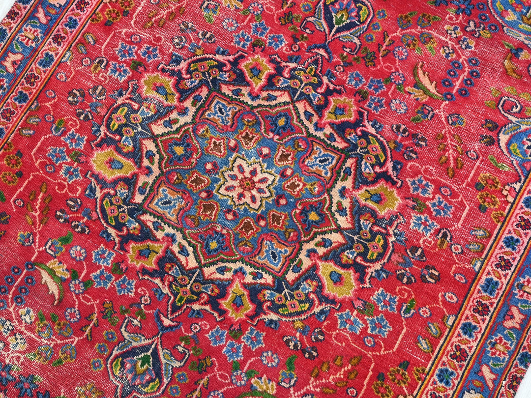 a red rug with a blue, yellow, and red design