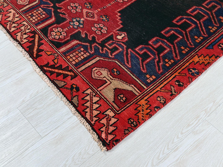 a red rug with a black border on a white floor