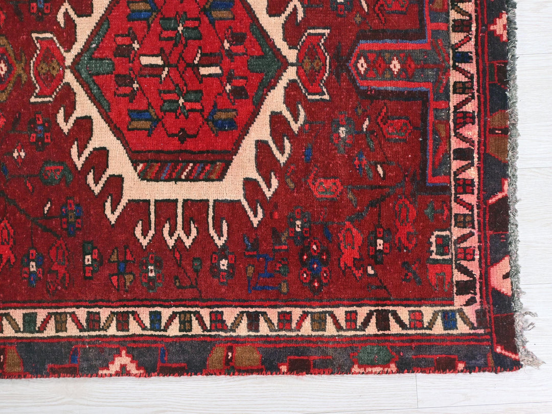 a red oriental rug on a white wooden floor