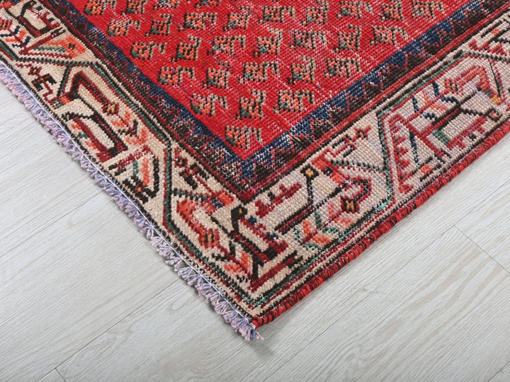 a red oriental rug on a white wooden floor