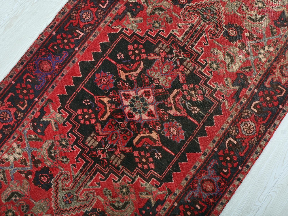 a red and black oriental rug on a white floor