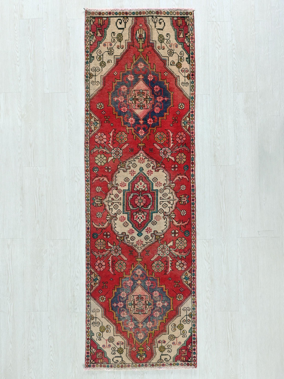 a red rug hanging on a white wall