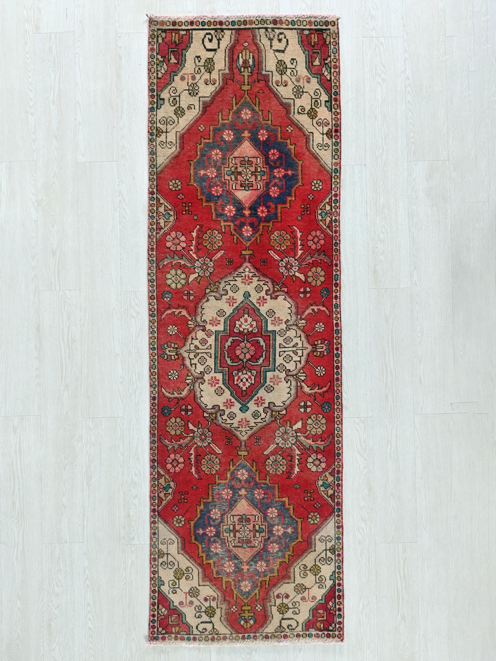 a red rug hanging on a white wall