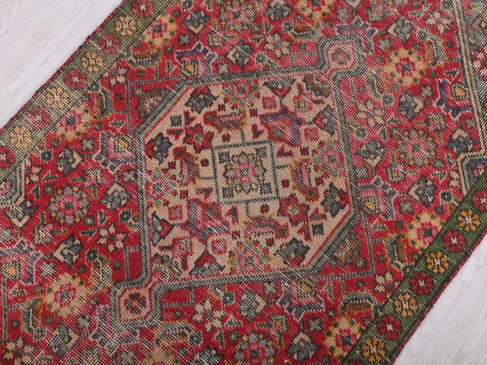 a red and green oriental rug on a wooden floor