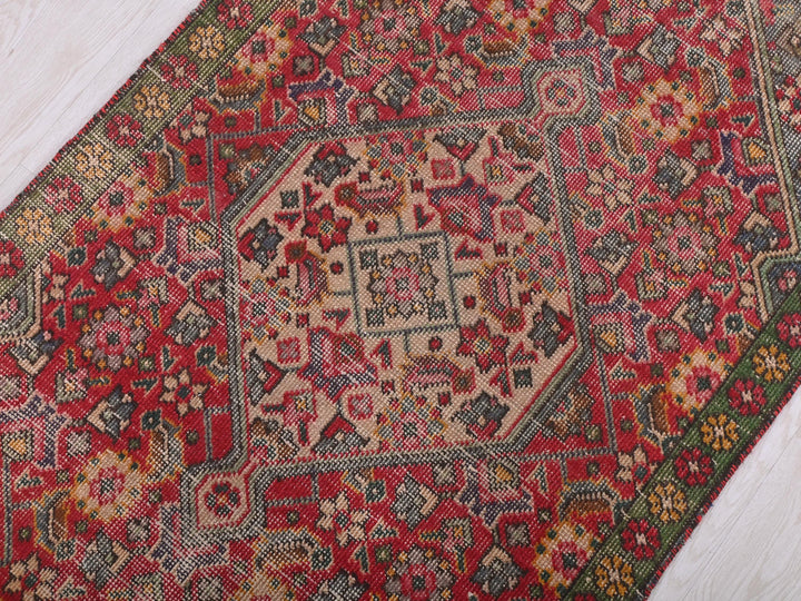 a red and green oriental rug on a wooden floor