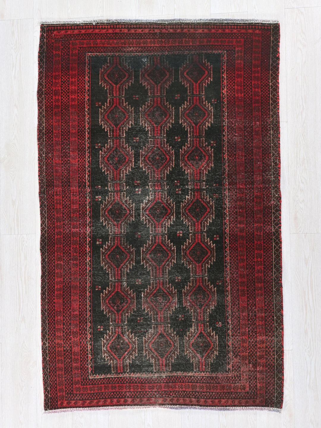 a red and black rug on a white floor