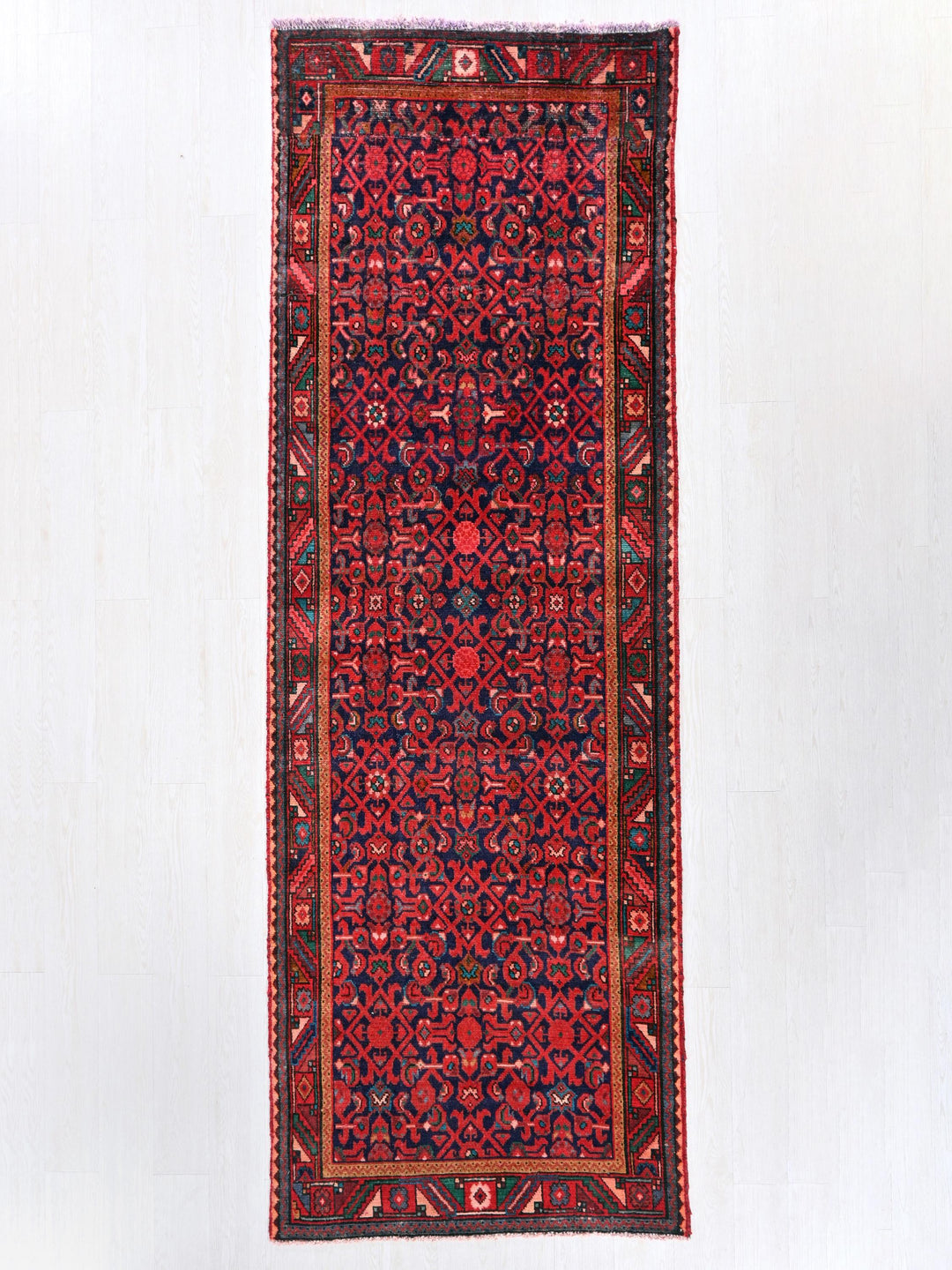 a red rug hanging on a white wall