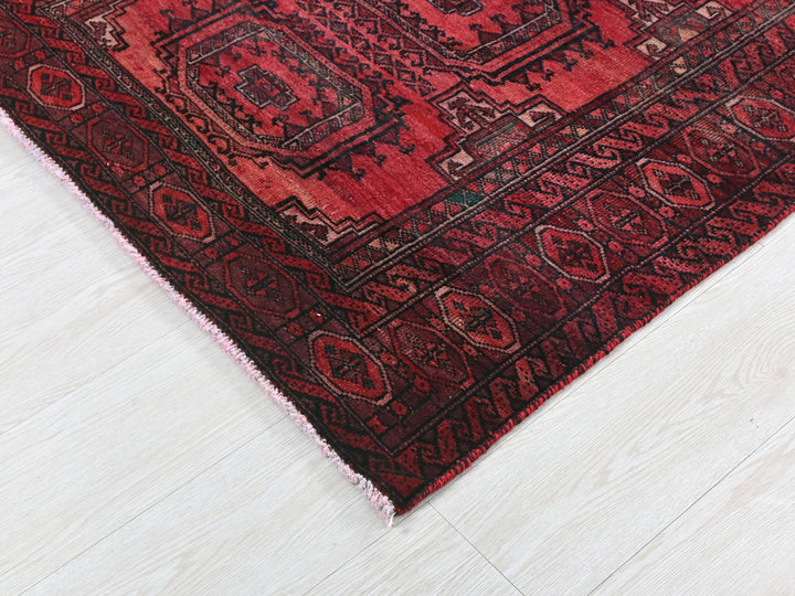a red oriental rug on a white wooden floor