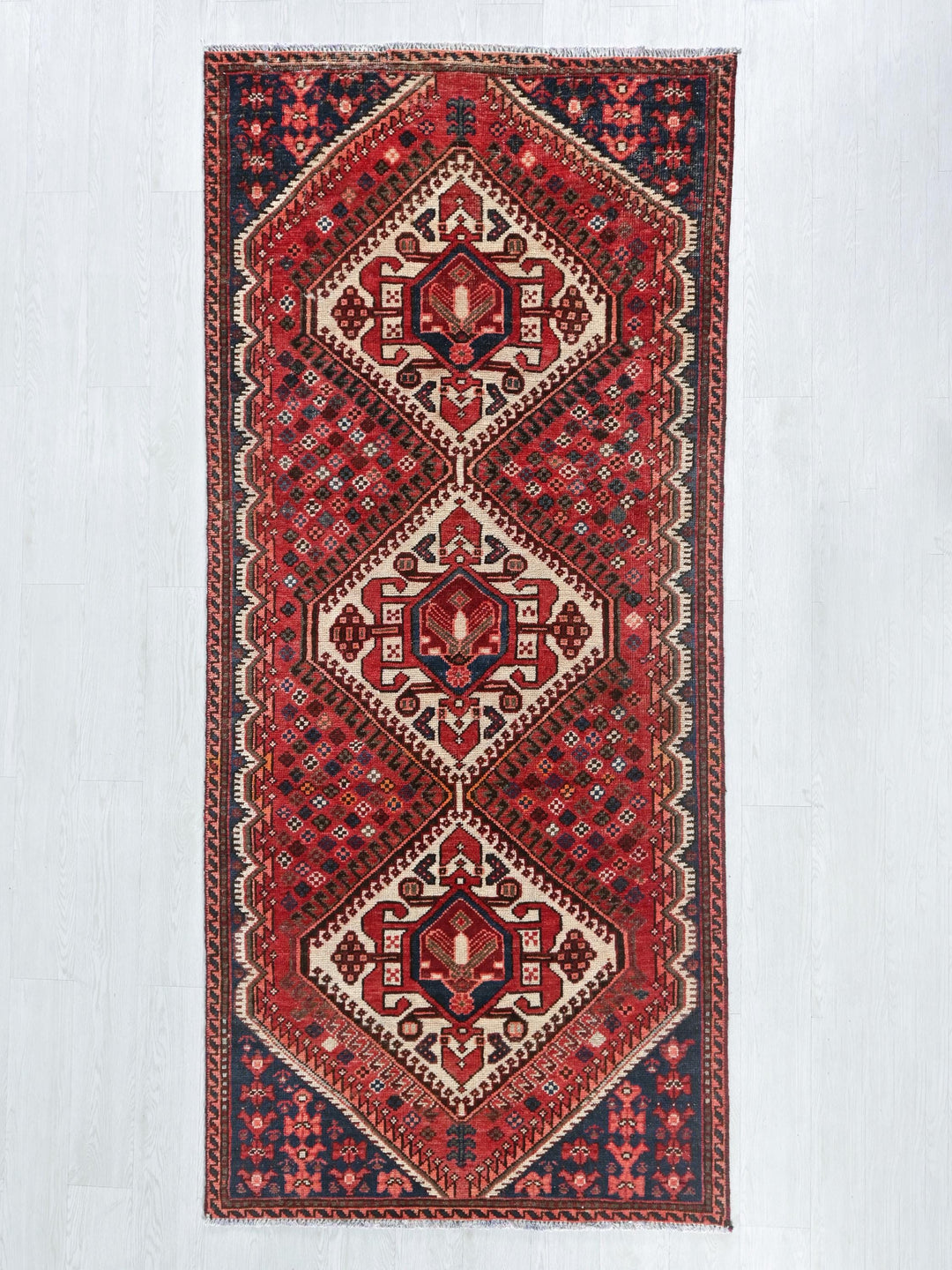 a red rug hanging on a white wall