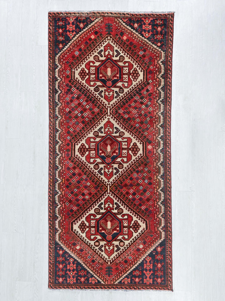 a red rug hanging on a white wall