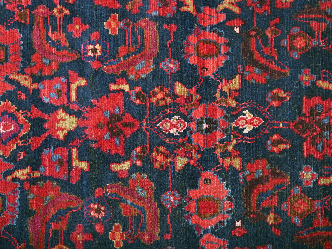 a blue and red rug with red flowers on it