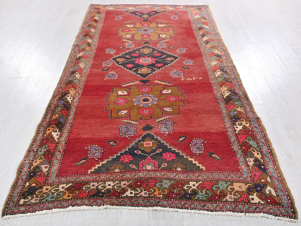 a red rug with a design on the middle of it