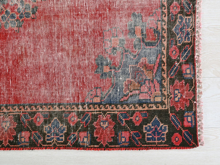 a red rug with a blue border on a white surface