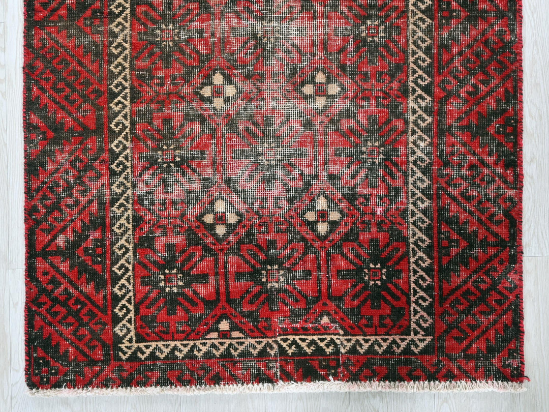 a red and black oriental rug on a wooden floor