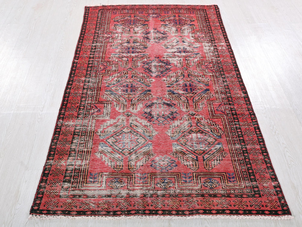 a red and black rug on a white floor