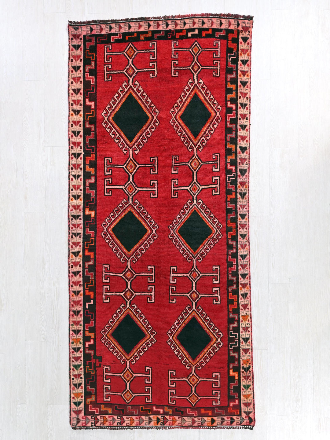 a red and black rug hanging on a wall
