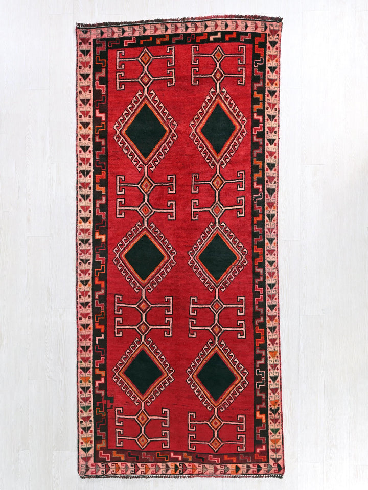 a red and black rug hanging on a wall