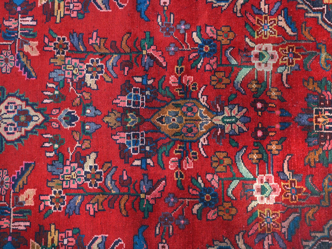 a red oriental rug with many colorful designs