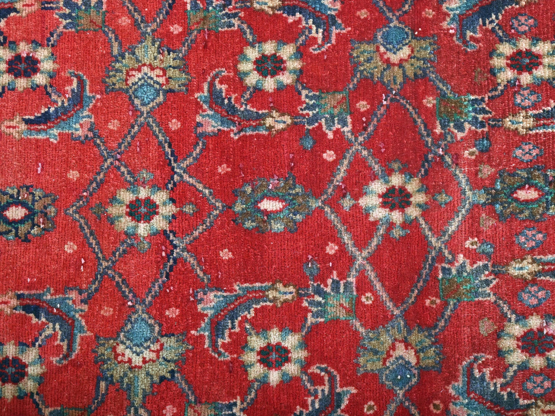 a close up of a red rug with blue and green flowers