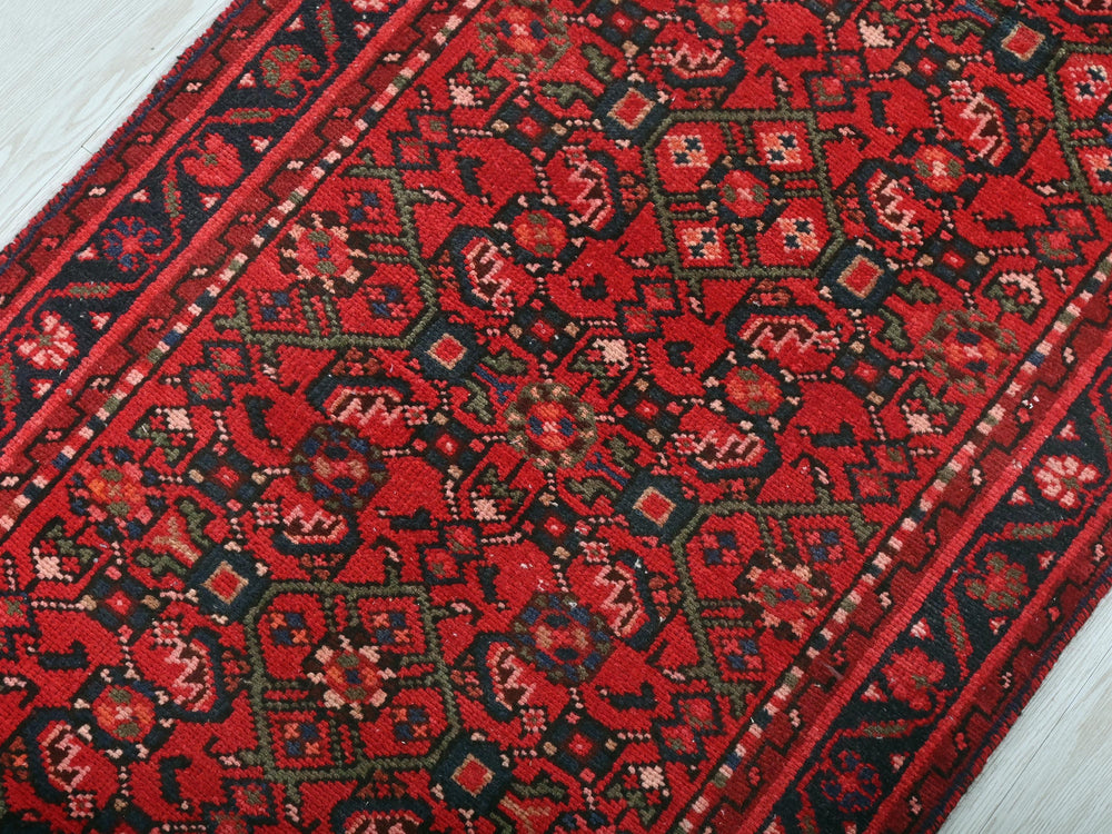 a red and black oriental rug on a white wooden floor