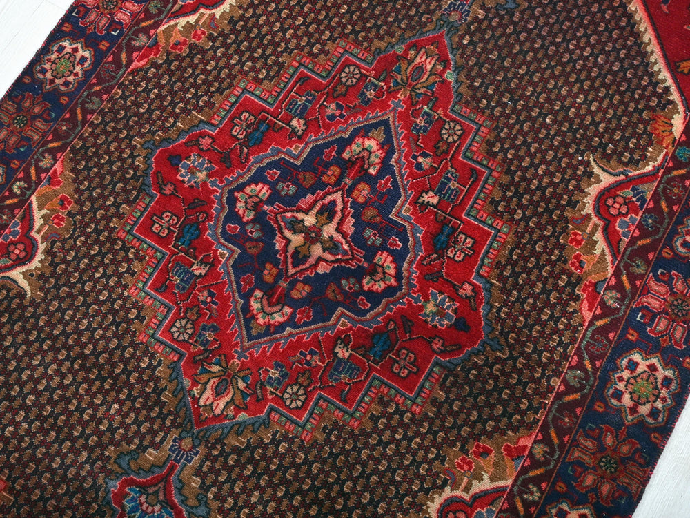 a red and blue oriental rug on a white floor