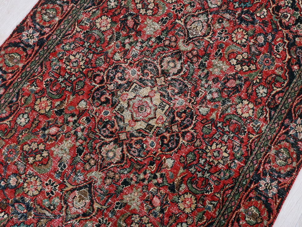a red and black rug on a white floor