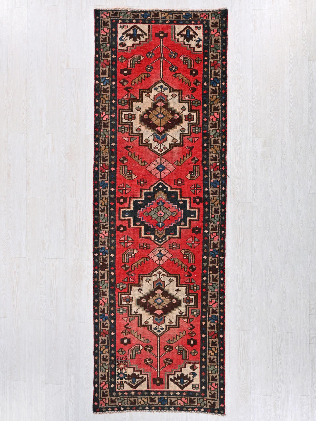 a red rug hanging on a white wall