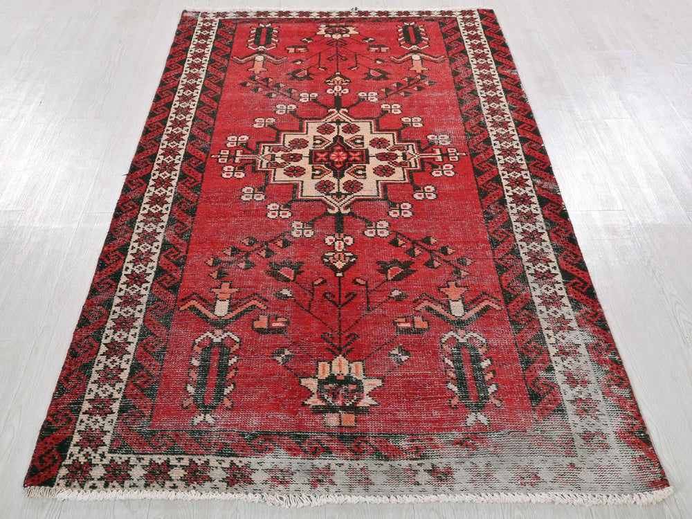 a red rug with a black border on a white floor