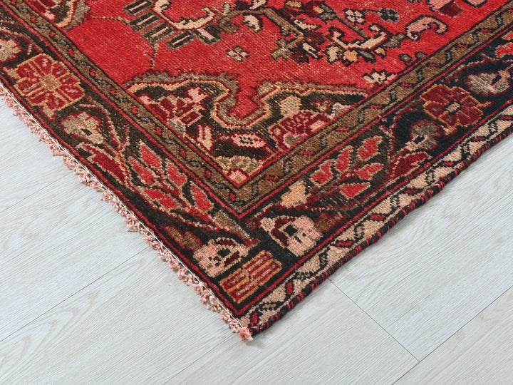 a red oriental rug on a white wooden floor