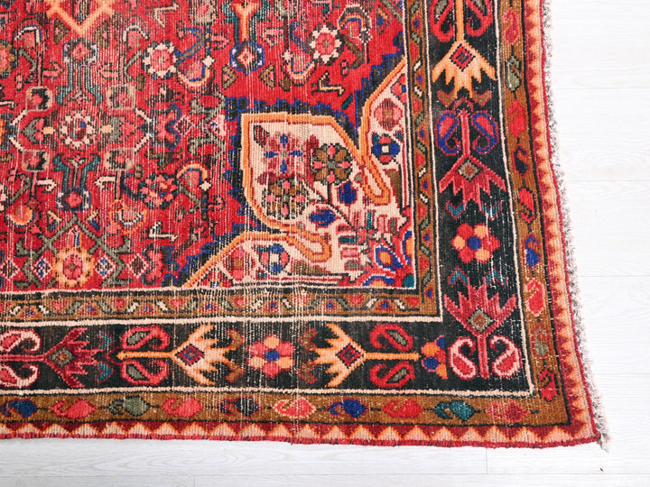 a red and black oriental rug on a white floor