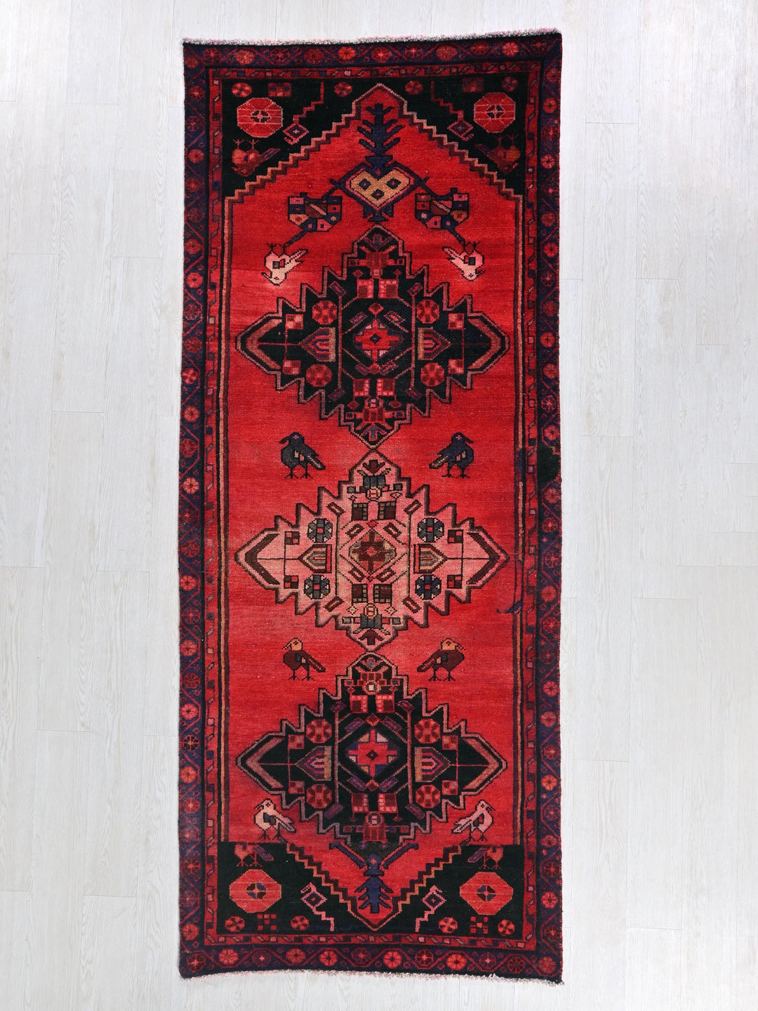 a red and black oriental rug on a white floor