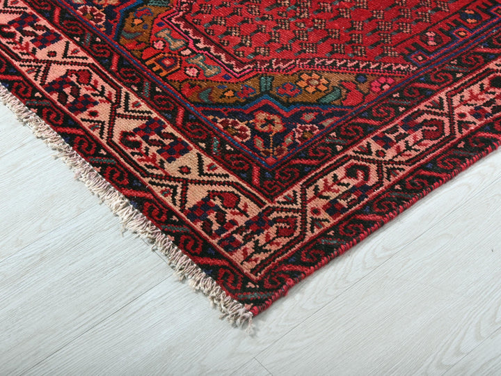 a red oriental rug on a white wooden floor