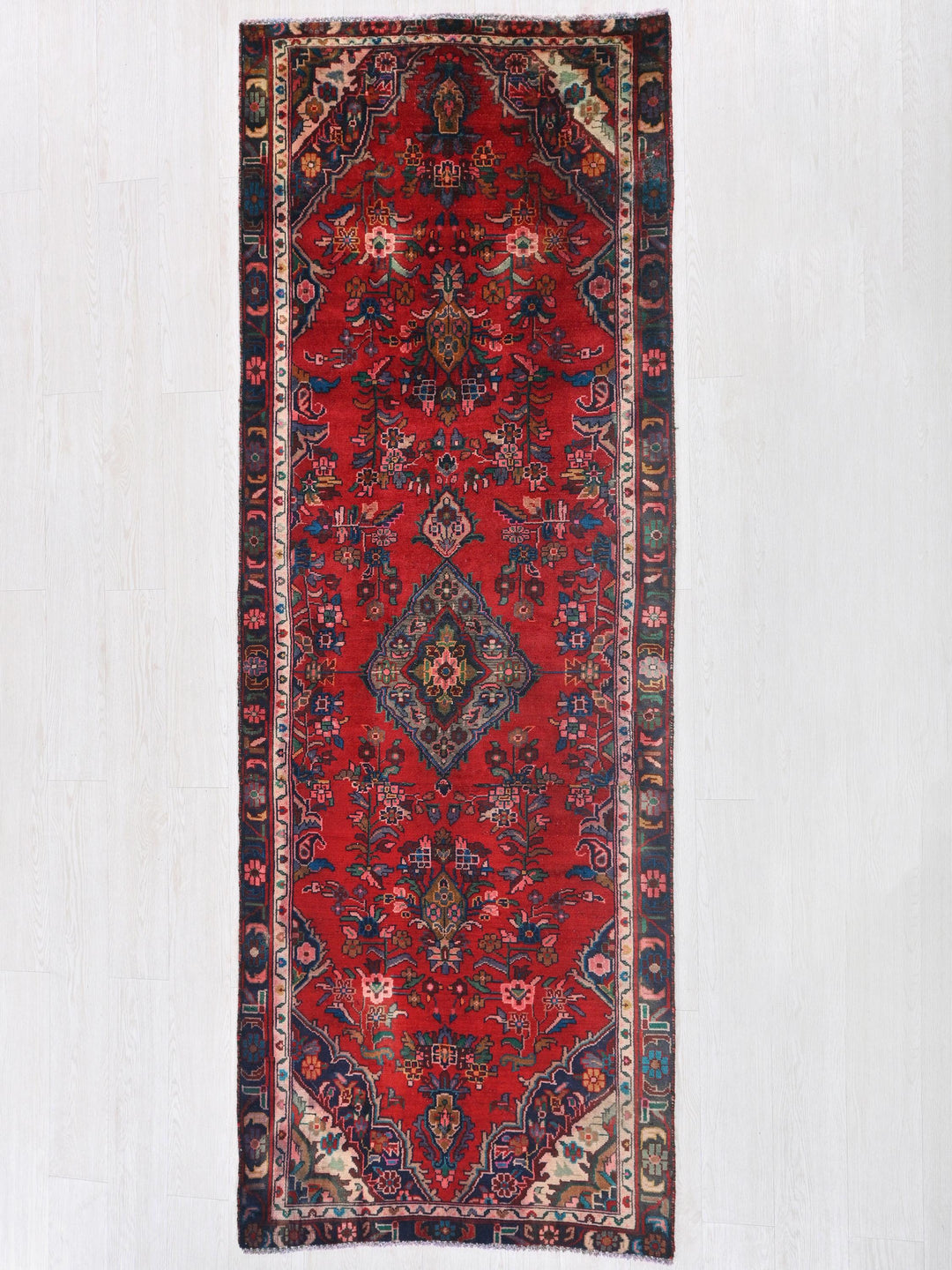 a red rug hanging on a white wall