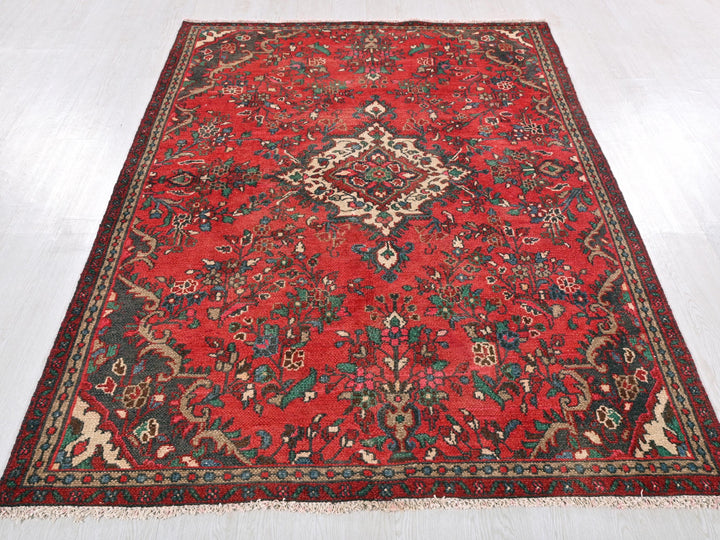 a red rug with a floral design on a white floor