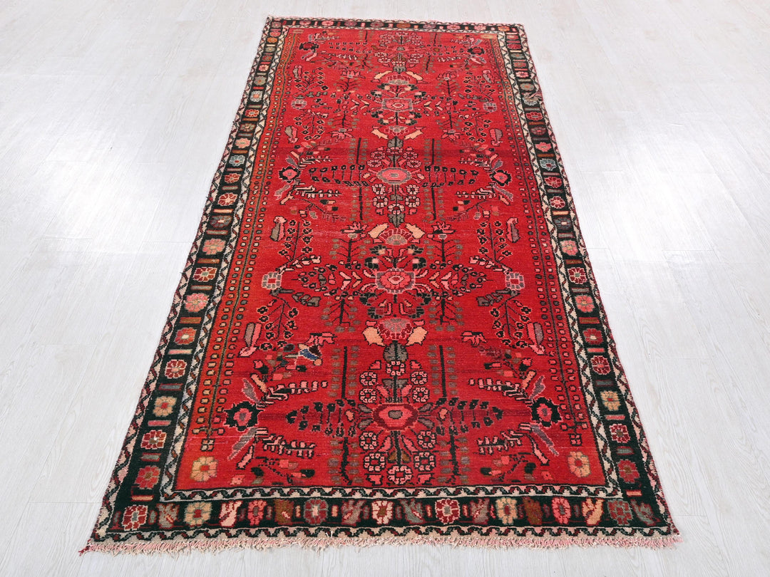 a red rug with a black border on a white floor