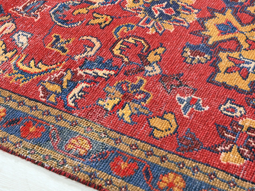 a close up of a red rug with a blue and yellow design